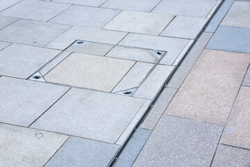 Cast iron rain or anover metal stormwater drainage system a downspout and slit tray with garbage on urban street paving walkway