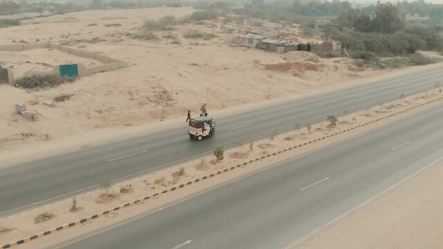 Aerial Of Auto Rickshaw Travelling Along M9 Motorway, Pakistan. Follow Shot