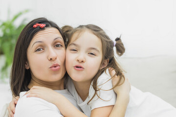 Close up photo of mother smiling with her daughter hugging together.