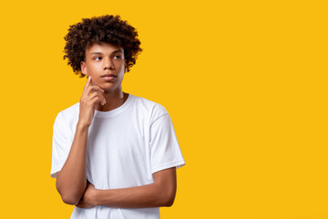Fototapeta na wymiar Pensive black teenager. Make decision. Confused yong african guy isolated on orange copy space. Create idea. Social tolerance. Advertising background