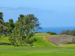 Golf play area and pacific ocean in the background. A paraglider is visible. Great parking area with a clear blue sky and sea view.