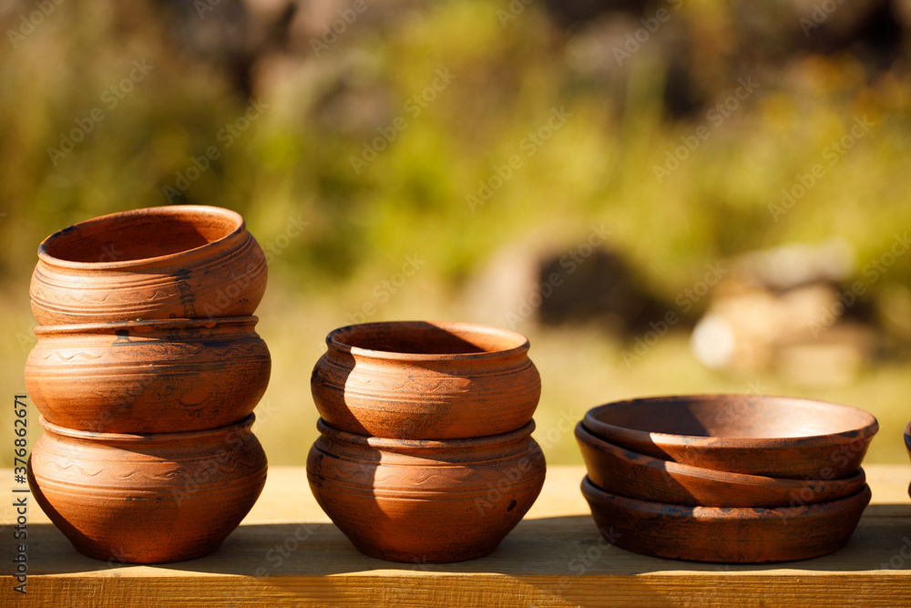 Poster clay plates stand in rows on a wooden shelf