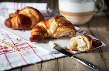 Fresh croissants with butter and coffee on a wooden table
