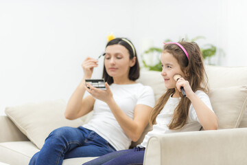 Photo of little girl with cosmetics and her mother near.