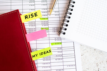 A business diary with colored tabs with inscriptions lies on financial charts.
