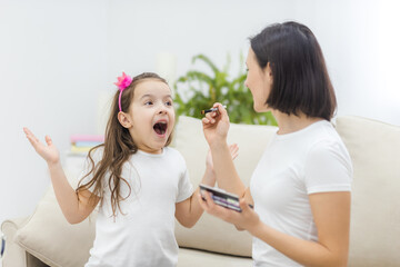 Photo of mother and daughter putting on make up in the living room.