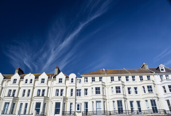 Fototapeta na wymiar Eastbourne seafront houses against blue sky with a feather cloud in a sunny day, England, UK