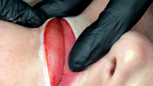 Cosmetologist making lips microblading permanent procedure using tattoo machine and pink pigment