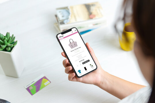 Girl shopping online with smart phone concept. Modern flat design commerce webiste with products. Credit card on desk in background