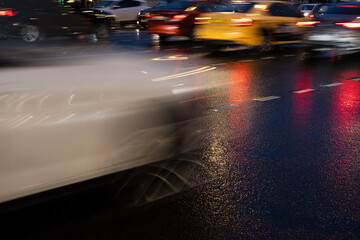 Fototapeta na wymiar Night traffic of cars. Cars in motion on wet asphalt. Flickering headlights in the evening city.
