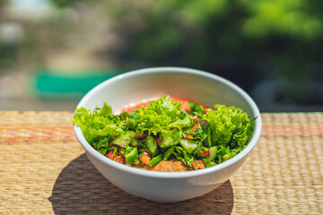 Raw vegan salad with green leaves mix vegetables in white bowl. Cooking recipe blended tomato carrot, parsley cilantro dill greenery cucumber, basil, bell pepper. Healthy food, vitamins for immunity