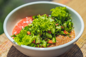 Raw vegan salad with green leaves mix vegetables in white bowl. Cooking recipe blended tomato carrot, parsley cilantro dill greenery cucumber, basil, bell pepper. Healthy food, vitamins for immunity