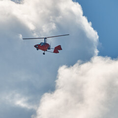 Gyrocopter, an ultra-light helicopter, circling in the sky under the clouds over Sylt, Germany