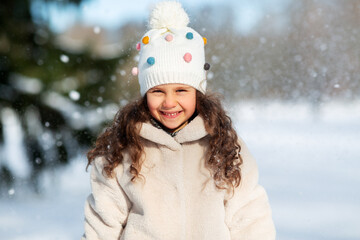 childhood, leisure and season concept - portrait of happy little girl in winter clothes outdoors at park