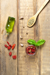 Sun-dried tomatoes in a glass jar with spices on a wooden background. Top view. Vertical orientation.