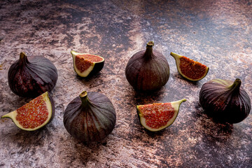 A few ripe, juicy figs whole and sliced beautifully laid out on a motley background. Figs are useful fruits with vitamins A, B, C.