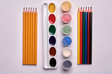 colored pencils, gouache paint, watercolor palette on white background