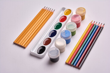 colored pencils, gouache paint, watercolor palette on white background