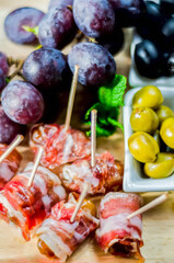 Delicious figs wrapped in bacon served with blue cheese, grapes and olives