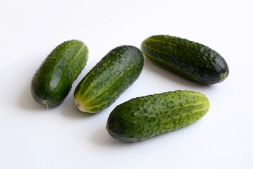 Several ripe juicy cucumbers lie on a white background