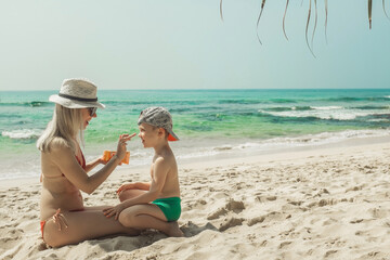 Mother applying sunscreen protection creme on cute little toddler boy face. Mom using sun blocking lotion to protect baby from sun during summer sea vacation. Children healthcare at travel time.