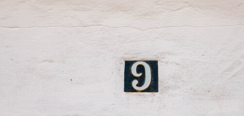 Decorative ceramic house number 9 tile on the wall, characteristic decorative element, number