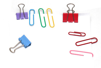 Colorful paperclips and binders on paper