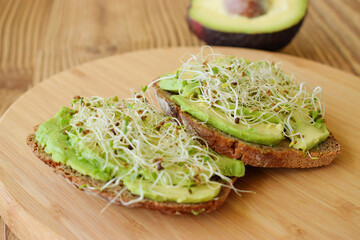 Sandwich of tender, juicy germinated alfalfa and avocado sprouts on slices of rye bread. This is a...