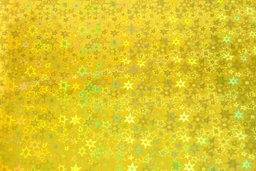 Blurred yellow trendy backdrop with stars. Bright holographic foil background. Colorful blue, red, purple background. Flat lay