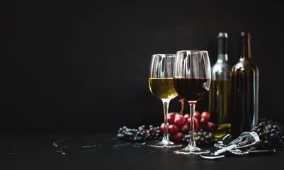 Rolgordijnen Wine in two wine glasses standing on a dark tabletop © Fattyplace