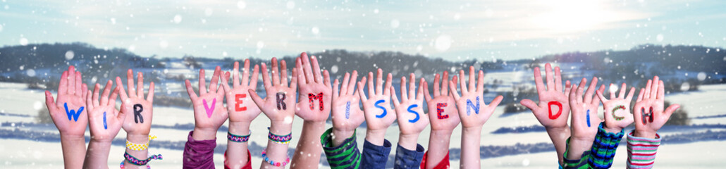 Children Hands Building Colorful German Word Wir Vermissen Dich Means We Miss You. Snowy Winter Background With Snowflakes