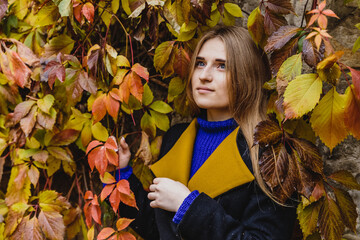 A beautiful blonde girl in a coat walks in the Park