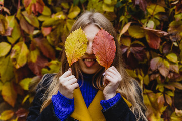 A beautiful blonde girl in a coat walks in the Park