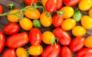 ripe appetizing yellow and red cherry tomatoes on wooden table