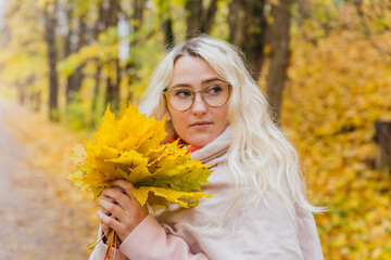 A beautiful blonde girl in a pink coat walks in the Park