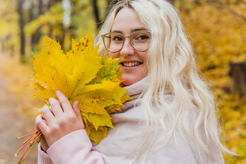 A beautiful blonde girl in a pink coat walks in the Park