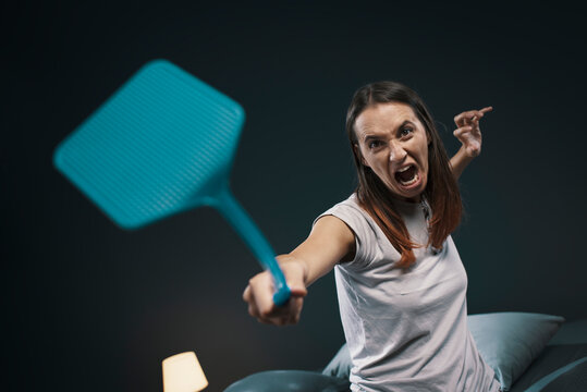 Angry woman killing mosquitoes with a fly swatter