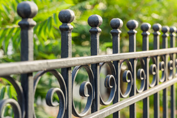 Beautiful decorative cast metal wrought fence with artistic forging. Iron guardrail close up.