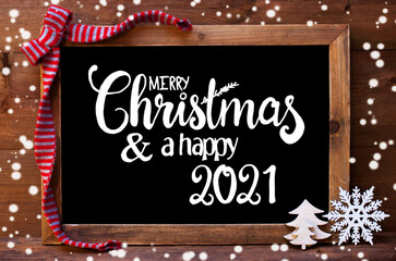 Fototapeta na wymiar Chalkboard With English Calligraphy Merry Christmas And A Happy 2021. Christmas Decoration Like Tree And Bow. Wooden Background And Snowflakes