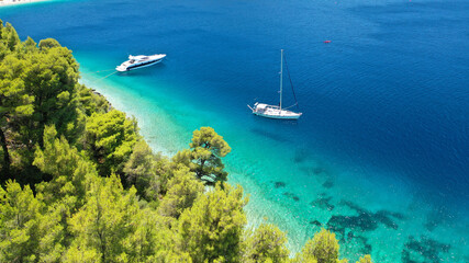 Fototapeta na wymiar Aerial drone photo of yacht anchored in famous crystal clear bay and turquoise beach of Panormos, Skopelos island, Sporades, Greece