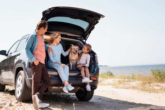 Selective focus of family with golden retriever traveling on car on beach