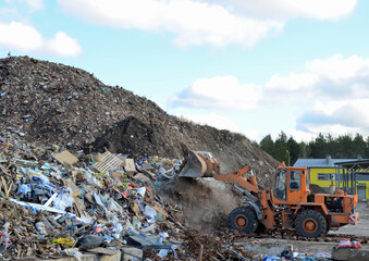 Front-end loader works in a landfill for the disposal of construction waste and other debris. Industrial waste treatment processing factory