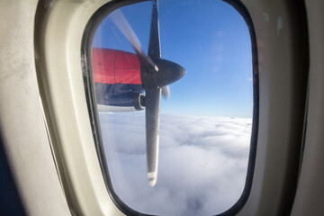 Naklejka premium Turbopropeller and a wing of a propeller plane with its typical helix seen from an aircraft window above in the sky, in flight, during a sunny afternoon