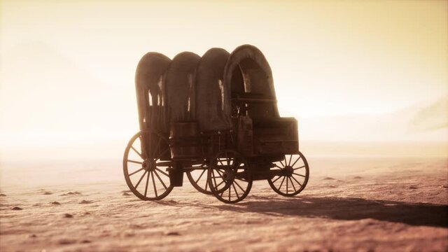 canvas covered retro wagon in desert at sunset