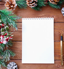 Notebook with pen and fir branches on wooden table