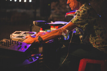 Dettaglio di un vecchio disk jockey al lavoro durante un evento serale di musica in un locale...