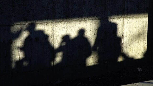 Shadows of the people on a concrete wall in slow motion
