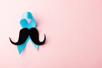 Black mustache paper and light blue ribbon, studio shot isolated on pink background, Prostate...