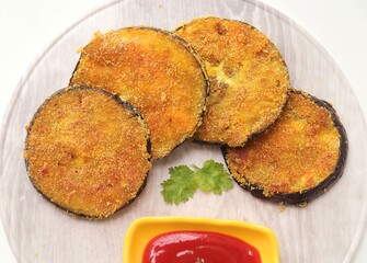 Indian side dish or appetizer  Vangyache Kaap, fried Eggplants, Crispy brinjal fry, Aubergine disks, served with tomato ketchup. With copy space