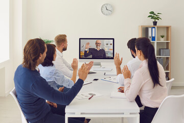 Company workers sitting in office having online meeting with their CEO using desktop computer